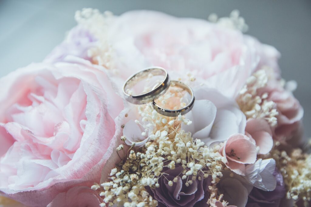 Photo by Beatriz Pérez Moya gold-colored bridal ring set on pink rose flower bouquet